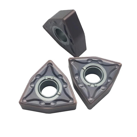 Three WNMG carbide turning inserts, triangular with central mounting hole, bronze-gray finish.