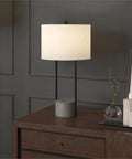 65.5 Inch Tall Floor Lamp With White Drum Shade In Blackened Bronze And Concrete Finish on wooden dresser