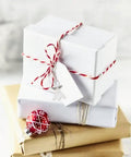 DIY Guardian Angel Pendant Kit packaged with Tibetan style beads, tied with red and white twine on top of gift boxes.