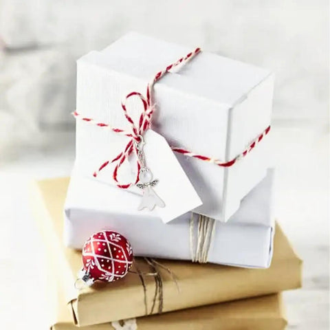 DIY Guardian Angel Pendant Kit packaged with Tibetan style beads, tied with red and white twine on top of gift boxes.