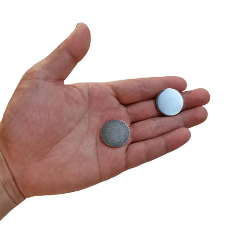 Two Slick Nickel Coated Steel Discs 0.98 Inch Diameter held in hand, showcasing smooth chamfered edges and nickel finish.