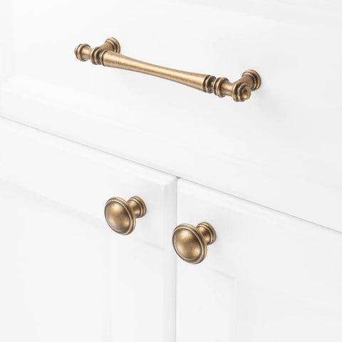 Ten Pack One And One Quarter Inch Antique Brass Kitchen Cabinet Knobs for cabinets, drawers and bathroom hardware on white doors.