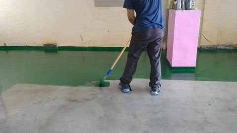 Person applying epoxy on floor wearing Epoxy Floor Spiked Shoes For Easy Garage Floor Coating Installations, 0.75 Inch Spikes