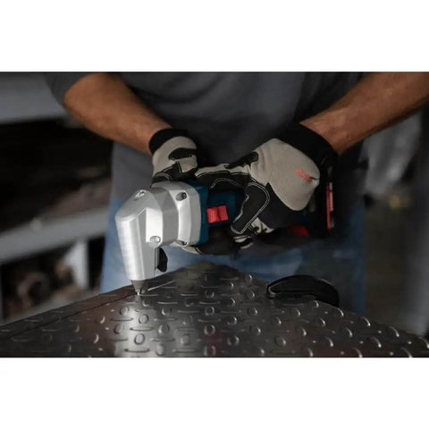 Person using 18V 16 Gauge Nibbler With Brushless Motor And Rotating Die Holder for cutting metal sheet, front view.
