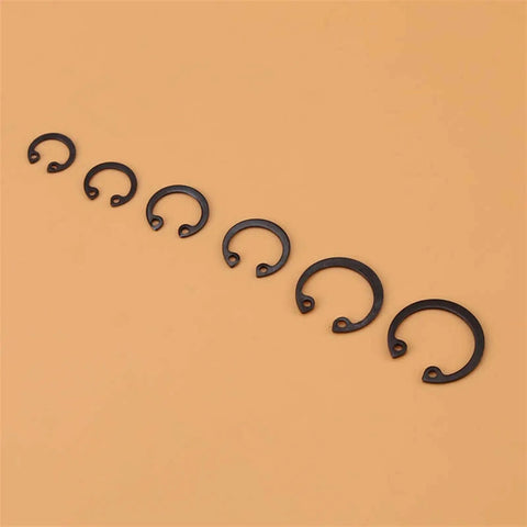 Assorted sizes of C clips from 100 Piece C Clip Snap Ring Kit With Box 11mm To 21mm C Type Retaining Rings Assorted Sizes Durable Steel Corrosion Resistant High Temp Tolerant Great For DIY Repairs Auto And Machinery displayed on orange surface