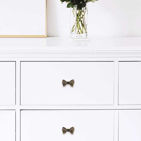 Copper Bowknot Cabinet Handle And Drawer Pull Kit In Vintage Brass Finish on white dresser drawer