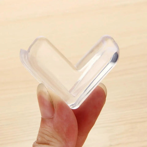 Close-up of a transparent corner protector held in hand, part of the White PVC Corner Protectors For Tables And Cabinets, Heavy Duty Adhesive Edge Guards, 30 Pack, Anti Collision Bumpers For Kidproofing Furniture And Preventing Injuries During Play Or Moving.