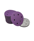 100 Pack 5 Inch 6Hole Alumina Sanding Discs With Super Sticky Hook And Loop Backing Ceramic Abrasive Pads For Metal Wood Projects Fast Dust Venting Design Grip Tight Swap In Seconds Without Tools Smooth Finish Every Time. Purple sanding discs stacked with holes for dust venting.