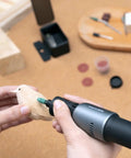 Person using Badass Sixty Piece Rotary Tool Accessory Crate for detailed carving of a wooden bird figurine.