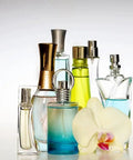 Assorted colorful perfume bottles with a white orchid flower on a light background.