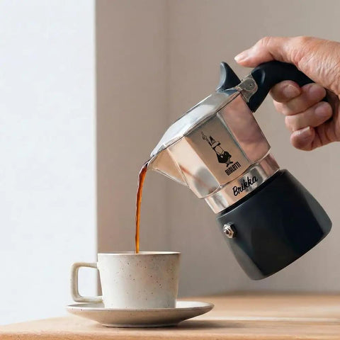 Brikka Moka Pot Crema Rich Stovetop Espresso Maker For Bold Italian Coffee At Home being poured into a cup from the sleek black design