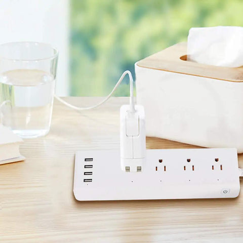 Totally Smooth Smart Power Strip With Four Wall Outlets And Four USB Charging Ports on a wooden table with a glass of water.