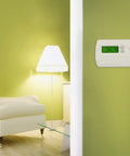 Living room with 7 Day Programmable Thermostat For Single Stage Heating And Cooling Systems With Backlit Display on green wall