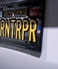Subdued 3D Embossed American Flag License Plate Frame With Black Gloss On Matte Finish For Car Truck Or SUV Featuring Thin Blue Line And Patriotic USA Pride attached to vehicle
