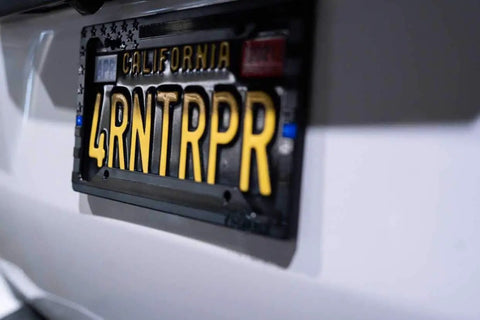 Subdued 3D Embossed American Flag License Plate Frame With Black Gloss On Matte Finish For Car Truck Or SUV Featuring Thin Blue Line And Patriotic USA Pride attached to vehicle