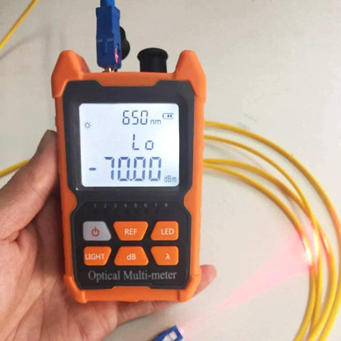 Orange handheld optical fiber tester with LCD readout and yellow fiber cable attached.