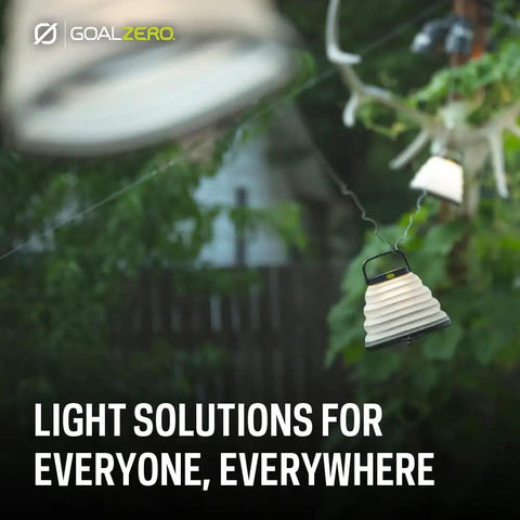 Crush Light Solar Powered Camping Lantern With Collapsible Design hanging outdoors among greenery
