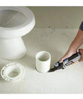 Person using 5 Amp Tool-Less Oscillating Tool Kit With Accessory Set For Cutting Sanding Grinding And Scraping on PVC pipe near toilet