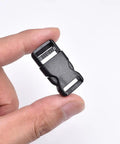 Close-up of a hand holding a black plastic half inch side release buckle, part of a 10 pack for backpack straps and DIY pet collars.
