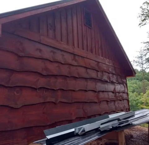 Premium One Coat Wood Stain Sealer For Log Homes In Black Canyon Red applied on log cabin exterior wall, showcasing deep red color.