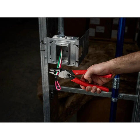 Person using 9 Inch Leverage Lineman Pliers With Crimper And Pipe Reaming Head to cut wires from electrical box installation.