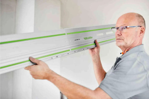 Man aligning Guide Rail Connector Set FSV2 for long workpieces with auto alignment and laser engraved markings in a workshop setting.