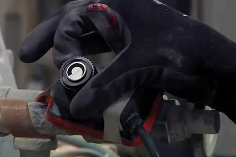 Gloved hand adjusting XtremeFLEX Mid-Temperature Silicone Heating Tape With Adjustable Thermostat Control around a pipe