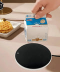 Keep Your Morning Coffee Piping Hot All Day Long With This Ultra Portable Cup Warmer And Smart Thermostatic Heating Coaster on a table.