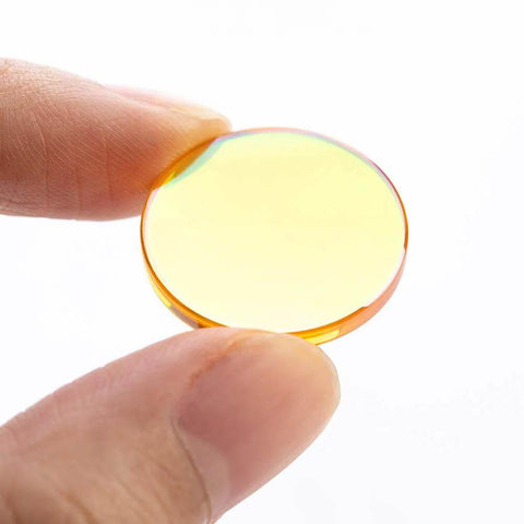 CO2 laser focal lens, 20mm diameter, orange-tinted glass held between fingers