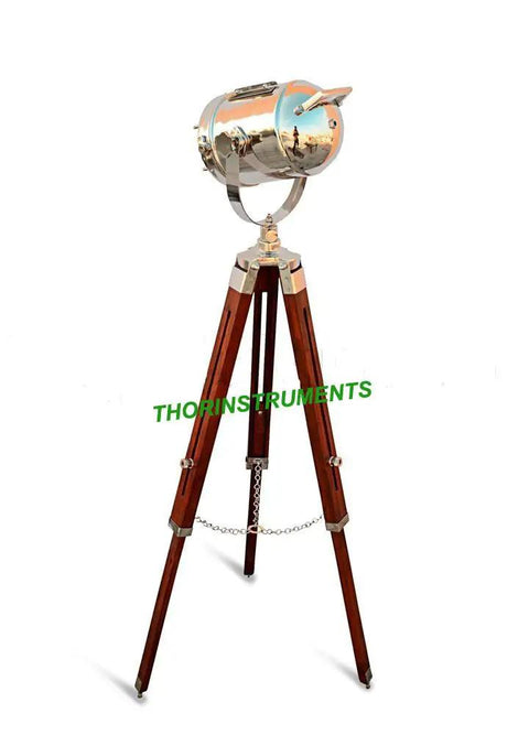 Chrome Spotlight Floor Lamp With Brown Wood Tripod Adjustable Height Studio Searchlight Lit Vintage Rustic Decor For Living Room Or Office Nautical Inspired Showpiece And Gift Idea, showing chrome spotlight on wooden tripod.
