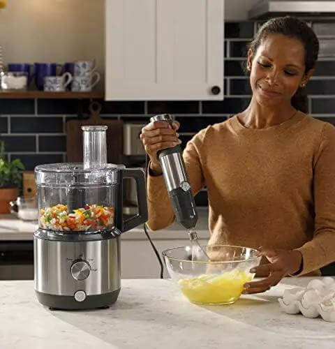 No Sweat 500 Watt Stainless Steel Immersion Blender With Removable Whisk And Spout Blending Jar For Thick Smoothies Quick Purees And Bold Homemade Sauces Dual Speed Hand Blender Kit in use blending ingredients.