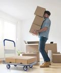 Man carrying boxes next to a Heavy Duty Foldable Push Cart Dolly With 330 Lb Capacity Collapsible Hand Truck in a room