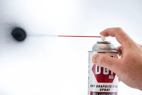Hand using 'Your Go To Dry Graphite Film Spray Anticorrosive Lubricant For Metal Surfaces Delivers Long Lasting Rust Protection And Smooth Operation In Harsh Weather And High Temperature Conditions' spraying black film on white background