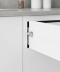 Push To Open Cabinet Latch Low Profile Gray Handleless Door Catch installed on a white kitchen cabinet.