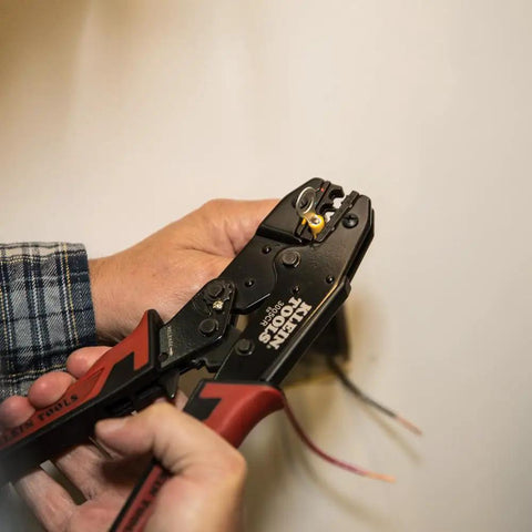 Hands using Pro-Grade Wire Stripper And Ratcheting Crimper Kit For Insulated Terminals on electrical wiring.