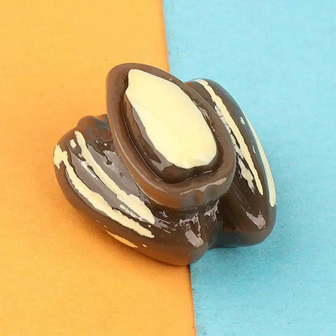 Close-up of a resin pistachio from the 15-Piece Realistic Miniature Nut Set For Dollhouses on a colorful background