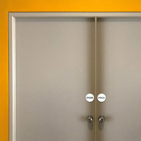 Two Inch Round Push Pull Door Signs Brushed Gold Set Of Two Durable Plastic With Strong Adhesive Foam Tape For Super Easy Install And Clear Legible Messaging In Offices Homes Or Commercial Doors on gray double doors