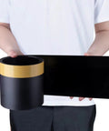 Person holding black roll and sheet of Under Couch Blocker Sofa Guard Sectional Connector Bumper That Stops Items From Sliding Under Furniture