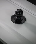 Matte Black Cabinet Knobs Four Pack With Wide Backplates installed on a white cabinet door, large ball knob visible