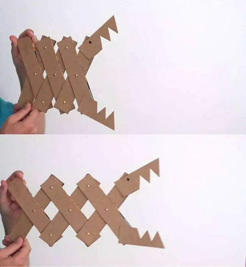 Hand holding a cardboard art piece resembling a fish with open and closed mouth angles.