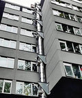 Built Tough Double Wall Stainless Steel Grease Duct 14 Inch Round 90 Degree Elbow Pre Insulated Commercial Exhaust Vent on building exterior.