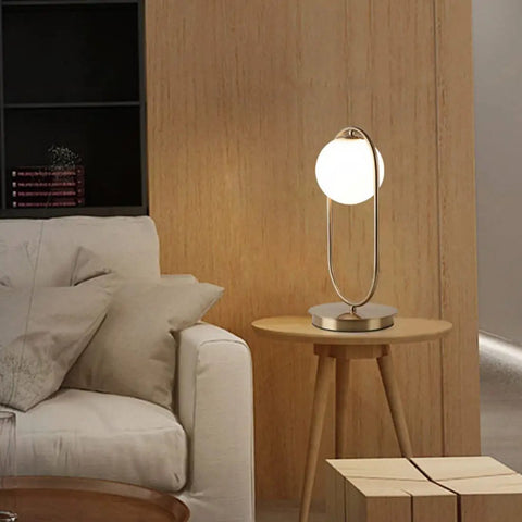 Dope Gold Globe Table Lamp With White Glass Shade on bedside table, mid century modern style, metal construction, living room setting