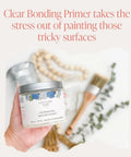 Close-up of a hand holding a 32 oz quart of Clear Bonding Primer for Chalk Style Furniture Prep with a brush and decor in background.