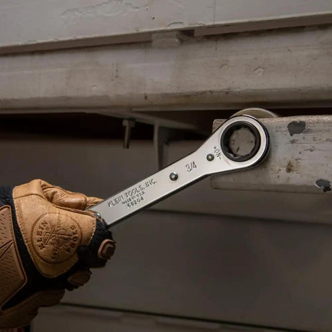 Close-up of a gloved hand using the Ratcheting Box Wrench Set SAE One Quarter Inch To Three Fourth Inch Five Piece Kit with Easy Reversing Dial.