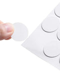 Fifty Four Pack 21 Mm Self Adhesive Screw Hole Covers White Pvc Dustproof Caps for cabinets being removed from a sheet.