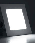 Square LED panel light emitting bright white light against a dark background