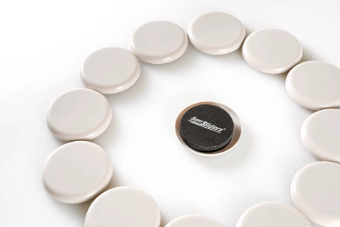 Round Two And Half Inch Reusable Furniture Sliders For Carpet Eight Pack Beige arranged in circle with one flipped showing black surface.