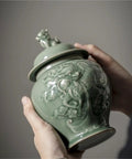 Top Tier Ceramic Airtight Tea Canisters For Loose Tea Leaves And Coffee Beans Hand Embossed Celadon Kirin Design in hand.