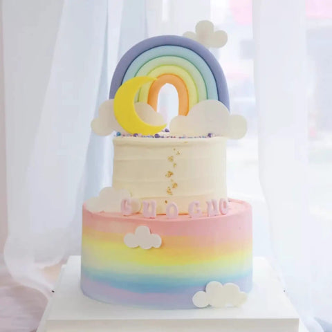 Two-tier pastel rainbow cake with fondant clouds and rainbow decoration made using Sweet Rainbow Cloud Fondant Molds Set Of 4.