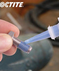 Loctite instant adhesive close-up applying to metal threaded bolt
